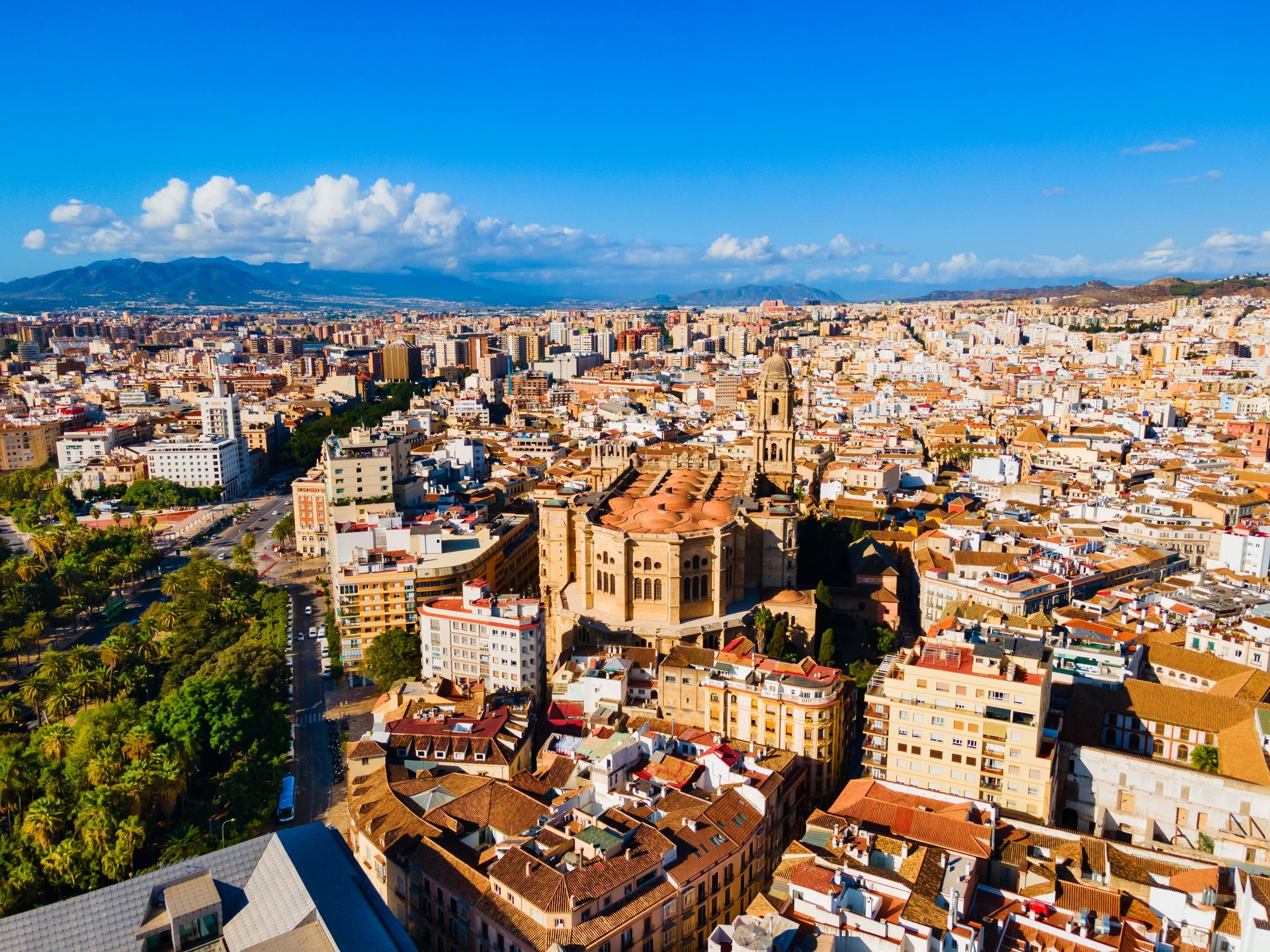 Aerial view of a cityscape with a large cathedral and surrounding buildings under a clear blue sky.